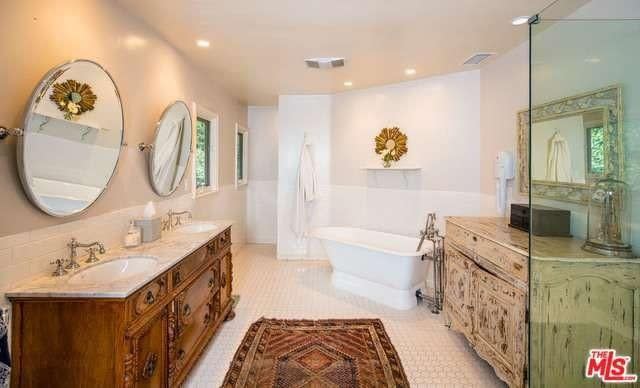 Antiqued vanities flank a modern shower and tub