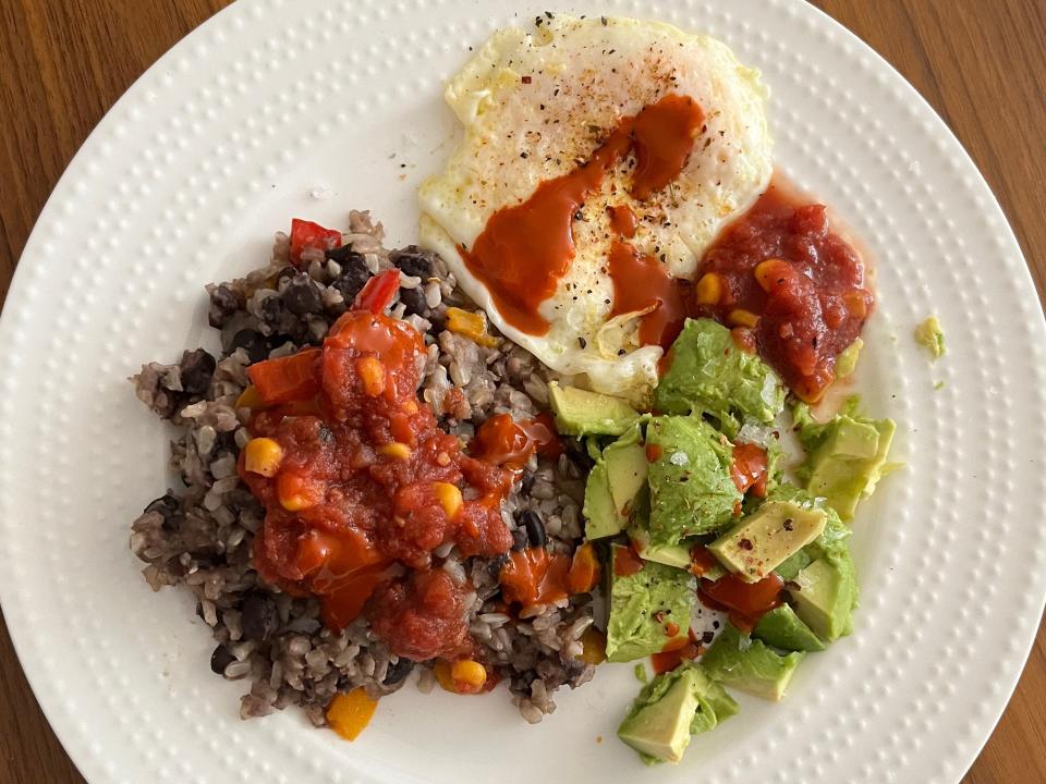 Customizing my gallo pinto (rice and beans) with an egg, avocado, and lots of hot sauce.