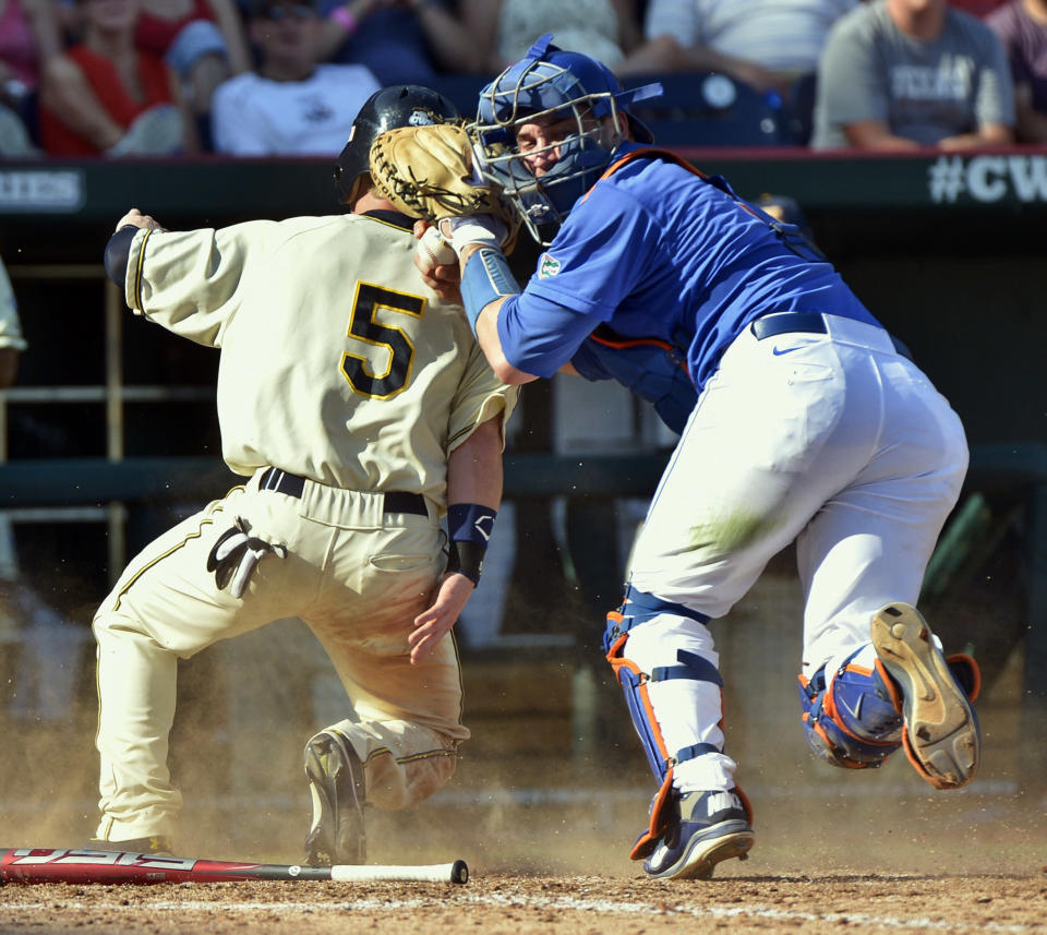 Kent State's T.J. Sutton (5) is tagged out at home plate by Florida catcher Mike Zunino after Alex Miklos reached second base on a fielder's choice in the fifth inning of an NCAA College World Series elimination baseball game in Omaha, Neb., Monday, June 18, 2012. (AP Photo/Ted Kirk)