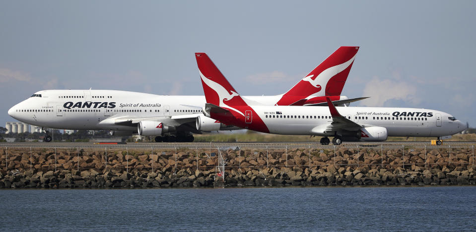 FILE - In this Aug. 20, 2015, file photo, two Qantas planes taxi on the runway at Sydney Airport in Sydney, Australia. The outbreak of the new virus threatens to erase $29 billion of this year's revenue for global airlines, mostly for Chinese carriers, as travel crashes worldwide, according to the International Air Transport Association. International airlines including British Airways, Germany’s Lufthansa, Australia’s Qantas and the three largest U.S. airlines have suspended flights to China, in some cases until late April or May. (AP Photo/Rick Rycroft, File)