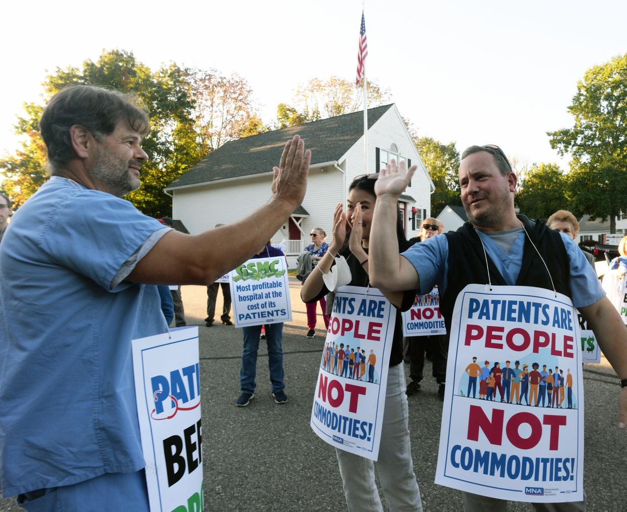 From left, a registered nurse gets a high-five from a fellow registered nurse, Branson Reynolds, after he addresses the crowd at a protest held outside the Brockton Fire Museum on Wednesday, Oct. 6, 2021 over staffing levels at Good Samaritan Medical Center.