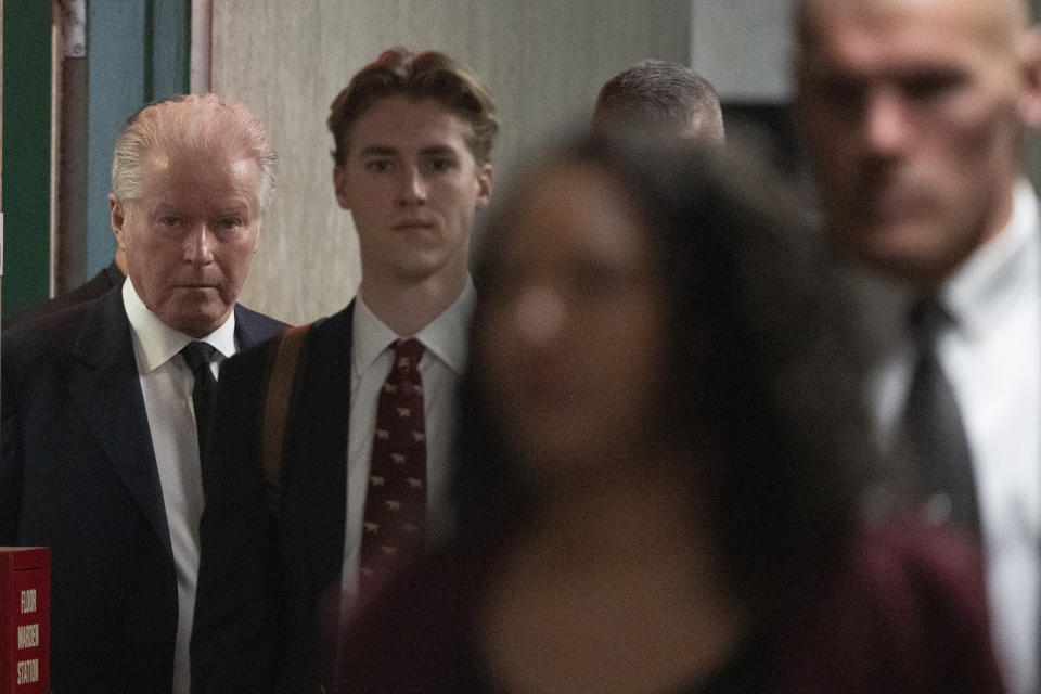 Musician Don Henley, left, surrounded by security, arrives at Supreme Court to testify, Monday, Feb. 26, 2024, in New York. The trial surrounding pages of draft lyrics to "Hotel California" and other Eagles hits is set to feature a star witness: Don Henley. The Eagles co-founder is scheduled to testify Monday at the criminal trial of three collectibles professionals. (AP Photo/Mary Altaffer)