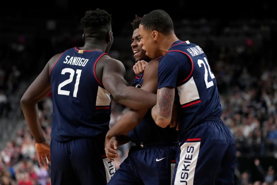 UConn forward Adama Sanogo (21), guard Nahiem Alleyne, middle, and guard Jordan Hawkins, right, celebrate after a play in the second half.