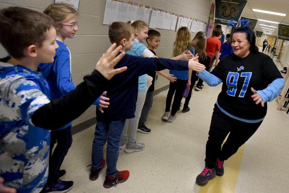 Barnes Elementary school principal Kirstie Mullins high-fives third graders as she was wearing the number of Detroit Lions defensive end Aiden Hutchinson Thursday.