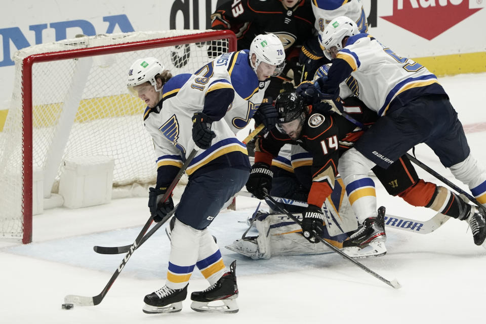 St. Louis Blues' Robert Thomas (18) moves the puck away from the net as Anaheim Ducks' Adam Henrique (14) is shoved by Blues' Colton Parayko (55) during the second period of an NHL hockey game Saturday, Jan. 30, 2021, in Anaheim, Calif. (AP Photo/Jae C. Hong)