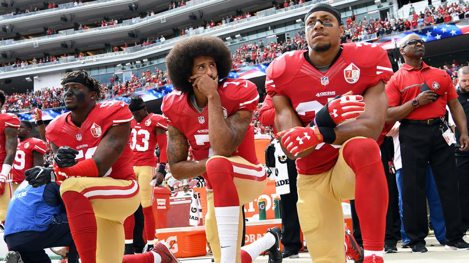 Pictured centre, Colin Kaepernick takes a knee during the national anthem before an NFL match.