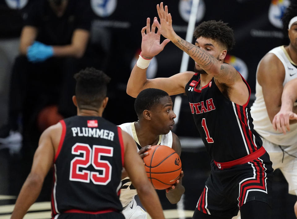 Colorado guard McKinley Wright IV, center, tries to slips between Utah guard Alfonso Plummer, front, and forward Timmy Allen for a shot in the second half of an NCAA college basketball game Saturday, Jan. 30, 2021, in Boulder, Colo. Utah won 77-74. (AP Photo/David Zalubowski)