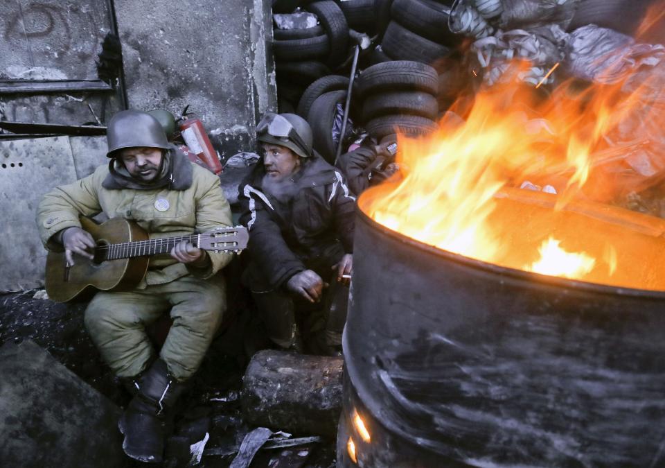 Anti-government activists entertain themselves next to a fire at a barricade in central Kiev, Ukraine, Friday, Jan. 31, 2014. Negotiations between the authorities and the opposition on finding a way out of the crisis appeared to have stalled on Thursday, after Yanukovych took an unexpected sick leave and told opposition leaders that it was now up to them to make concessions. (AP Photo/Efrem Lukatsky)