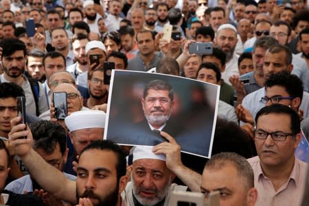 A man holds a picture of the former Egyptian president Mursi during a symbolic funeral prayer in Istanbul