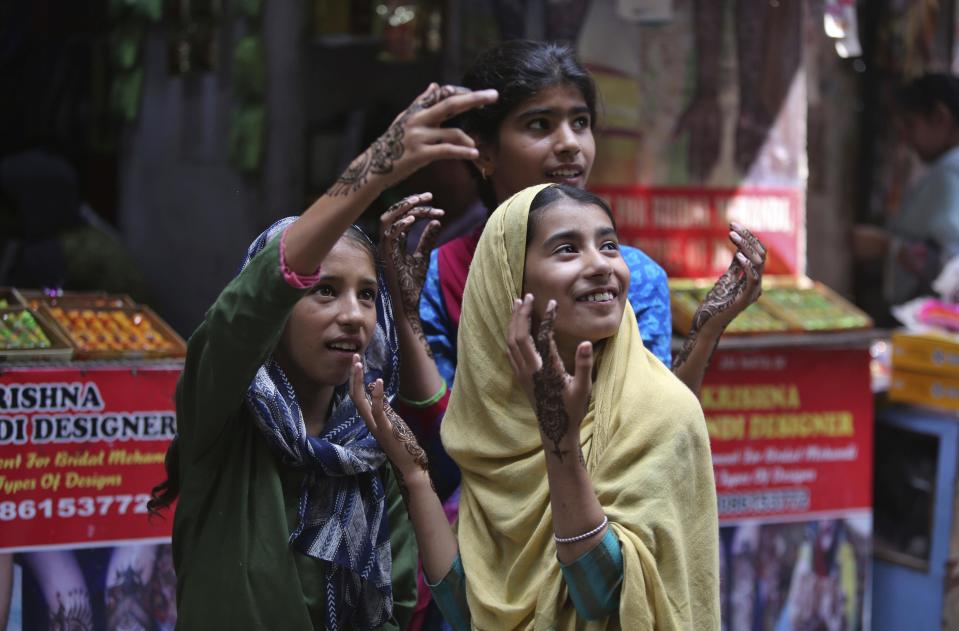 Girls gesture after getting henna decorations on their hands on the eve of Eid al Adha, in Jammu, India, Sunday, Aug.11, 2019. Authorities in Indian-administered Kashmir said that they eased restrictions Sunday in most parts of Srinagar, the main city, ahead of an Islamic festival following India's decision to strip the region of its constitutional autonomy. There was no immediate independent confirmation of reports by authorities that people were visiting shopping areas for festival purchases as all communications and the internet remain cut off for a seventh day. (AP Photo/Channi Anand)