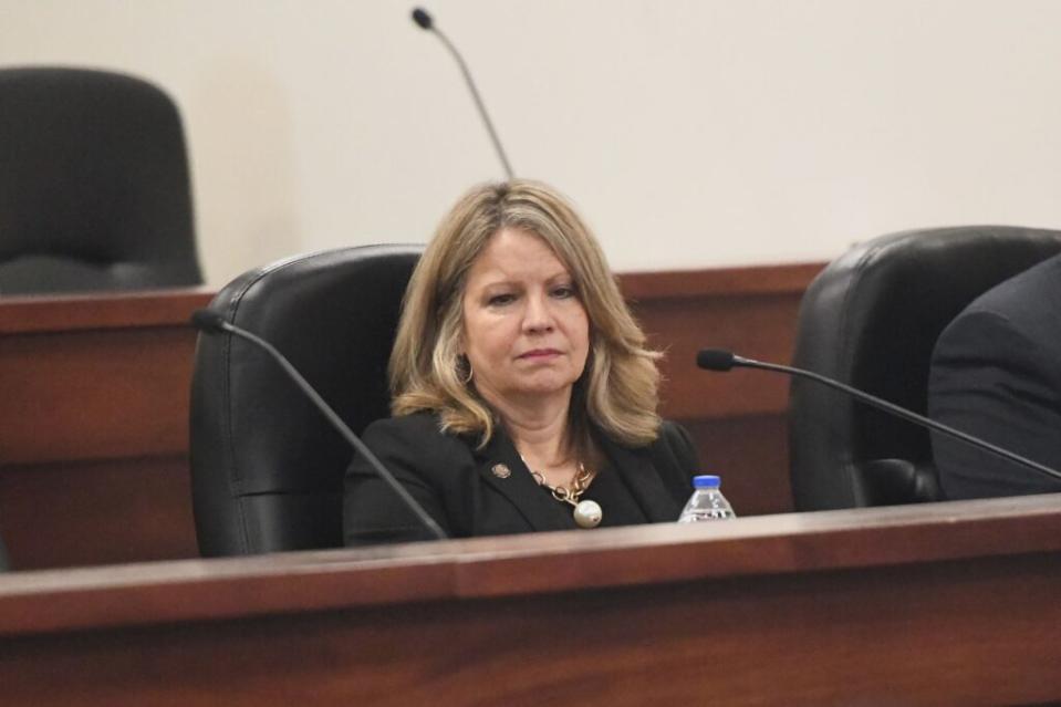 A woman sits behind a microphone.