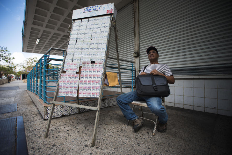 Lottery vendor Manuel Almonte waits for customers in the sparce Rio Piedras area of San Juan, Puerto Rico, Wednesday, April 17, 2019. The heaviest population drops in Puerto Rico since Hurricane Maria have occurred in metropolitan areas such as the capital and the city of Ponce. (AP Photo/Carlos Giusti)