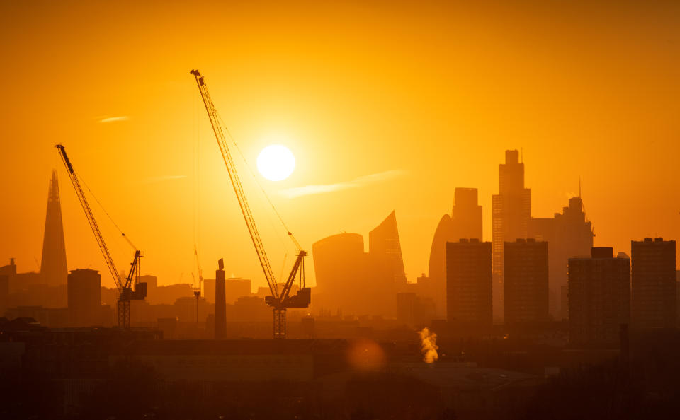 The sun sets behind tower cranes and the London skyline, including the Shard (left) and skyscrapers in the city financial district of London. (Photo by Dominic Lipinski/PA Images via Getty Images)