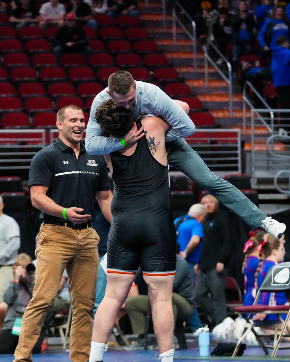 West Delaware's Cam Geuther hugs his coach after defeating Independence’s Korver Hupke at 285 pounds during the semifinals of the Class 2A state wrestling tournament Friday.