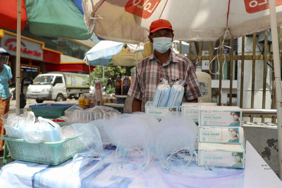 A vendor selling face masks and shields waits for customers at a roadside shop in Yangon, Myanmar, Thursday, Sept. 10, 2020. Myanmar is accelerating efforts to control the spread of the coronavirus, which now has impinged on the upcoming November 8 general election, as campaigning has been ordered suspended in several areas locked down to control the spread of the virus. (AP Photo/Thein Zaw)