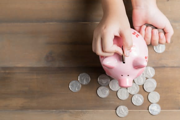 Piggy bank with quarters surrounding on the table.