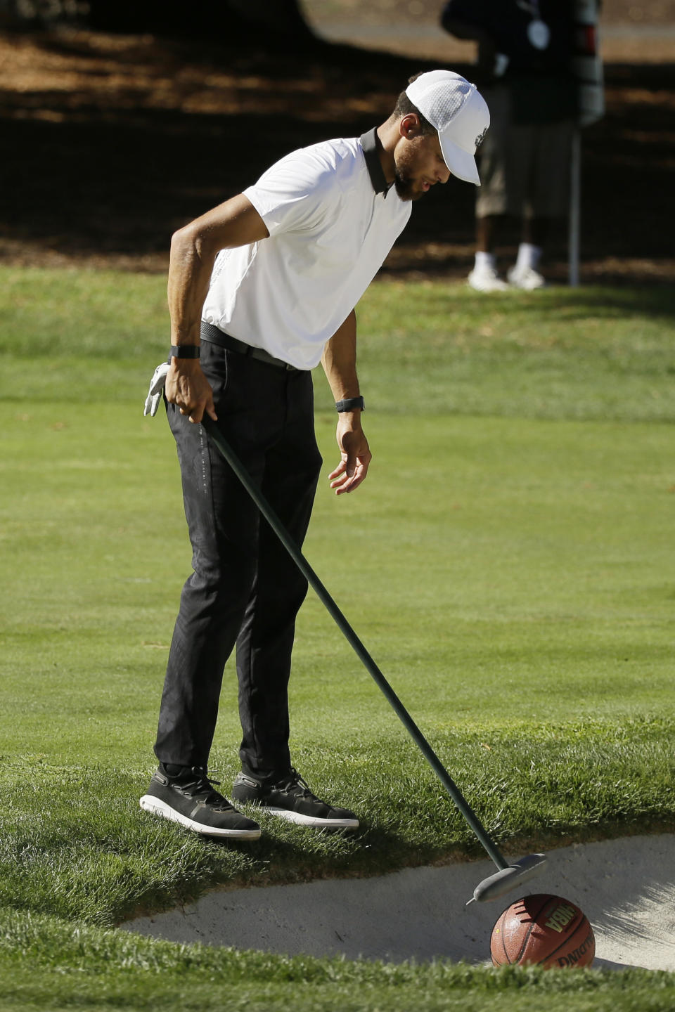 Stephen Curry uses a rake to retrieve a basketball from a bunker below the 17th green of the Silverado Resort North Course during the pro-am event of the Safeway Open PGA golf tournament Wednesday, Sept. 25, 2019, in Napa, Calif. (AP Photo/Eric Risberg)