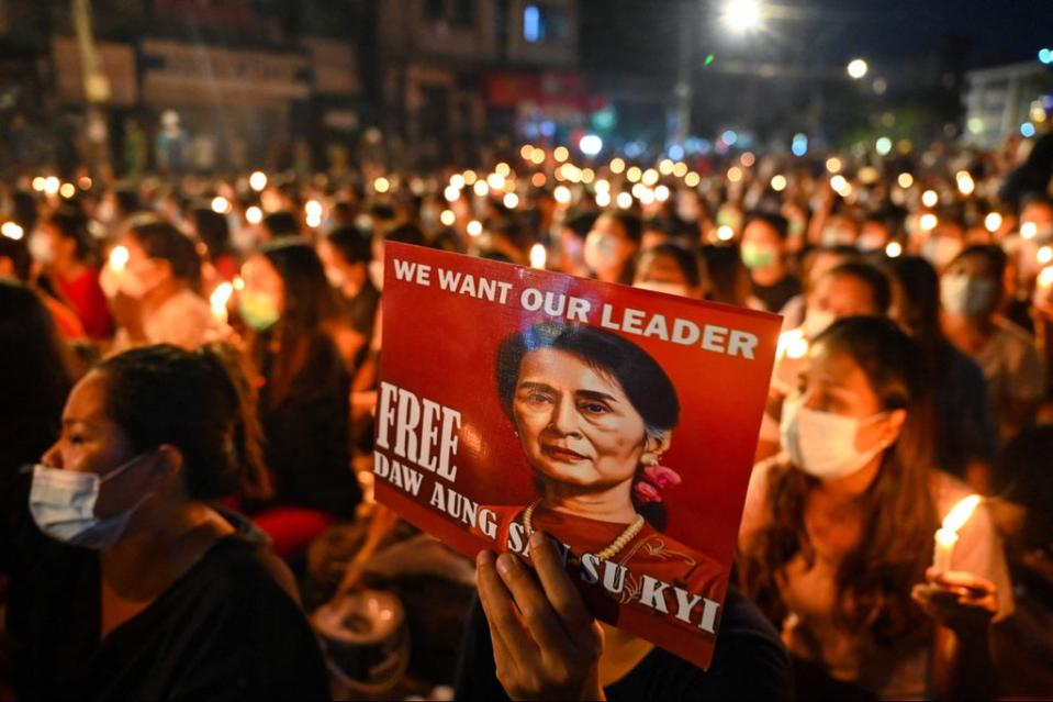 In this file photo taken on March 13, 2021, a protester holds a poster with an image of detained civilian leader Aung San Suu Kyi during a candlelight vigil to honour those who have died during demonstrations against the military coup in Yangon. (AFP via Getty Images)