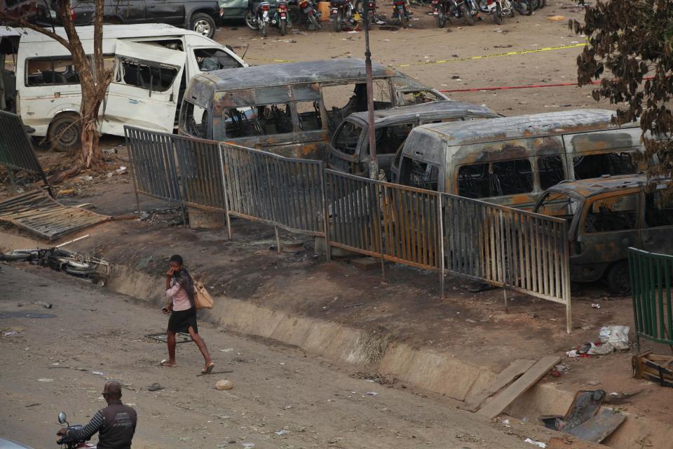 A woman walk past burnt out buses at the scene of an explosion at a bus park in Abuja, Nigeria, Tuesday, April. 15, 2014, with at least 72 feared dead as the blast destroyed more than 30 vehicles and caused secondary explosions as their fuel tanks exploded and burned. The Tuesday attack just miles from Nigeria's seat of government increases doubts about the military's ability to contain an Islamic uprising that is dividing the country on religious lines as never before.(AP Photo/ Sunday Alamba)