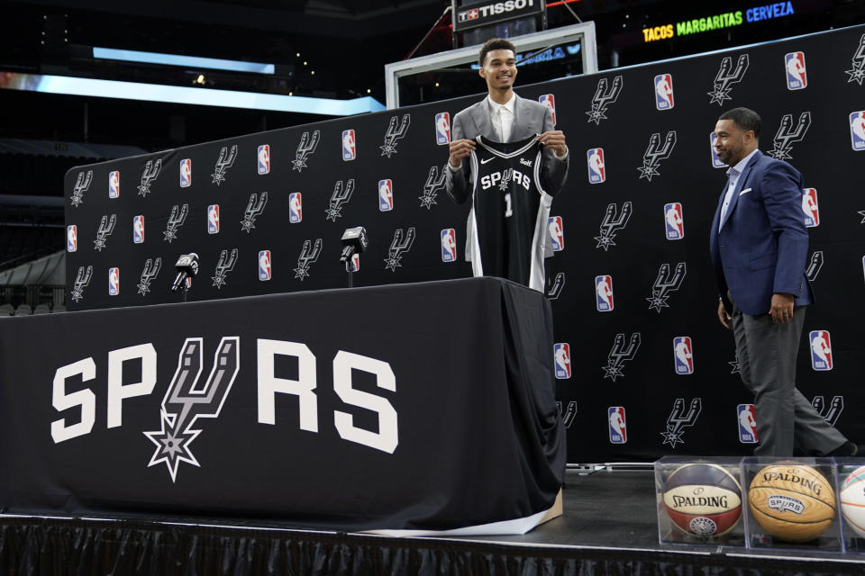 San Antonio Spurs NBA basketball first round draft pick Victor Wembanyama holds his jersey as Spurs general manager Brian Wright, right, looks on during a news conference in San Antonio, Saturday, June 24, 2023. (AP Photo/Eric Gay)