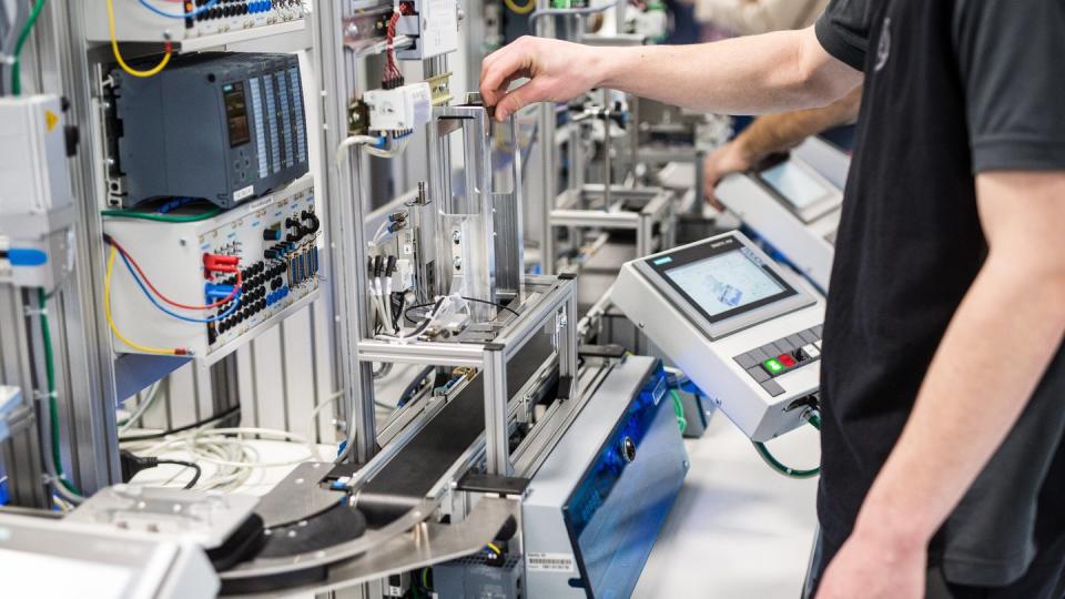 Auszubildende arbeiten im Daimler-Ausbildungszentrum in einem Industrie-4.0-Labor an einem Modell, das eine moderne Automobilproduktionsstraße nachempfindet.