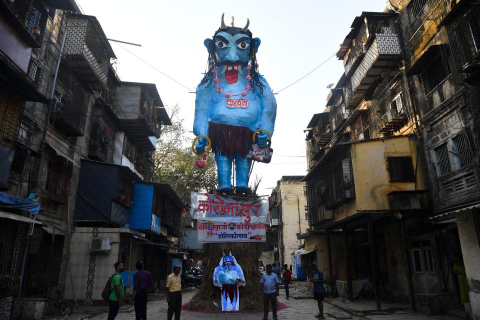 Residents stand near a Holika Dahan effigy of the Coronavirus demon - 'Coronasur' in Mumbai.