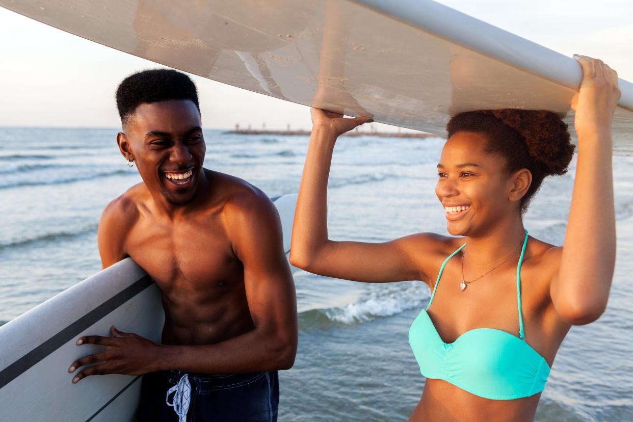 Young couple at the beach holding surf boards