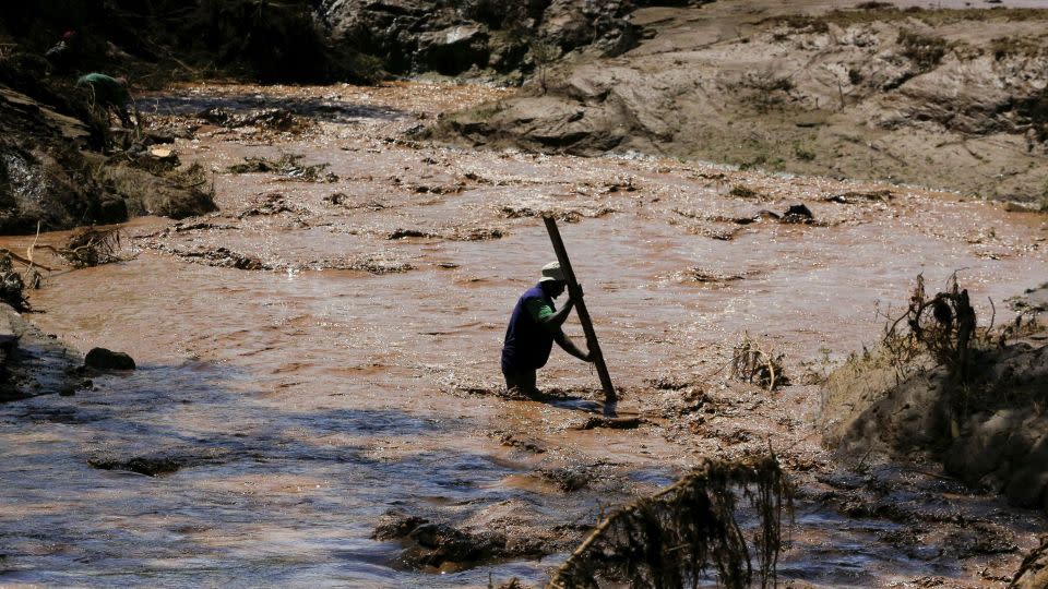 A man uses a stick to cross a river after heavy flash floods wiped out several homes when a dam burst, following heavy rains in Kamuchiri village of Mai Mahiu, Nakuru County, Kenya on April 29, 2024. - Thomas Mukoya/Reuters