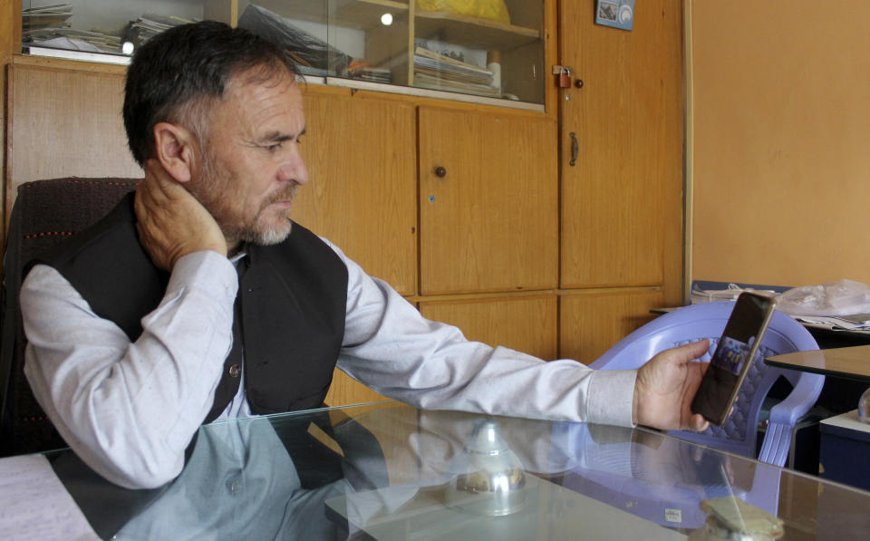 Pakistani tour operator Haji Ghulam Muhammad, who arranged the trip of missing Korean climber Kim Hong Bin with others, views photos on his cell phone during an interview at his office in Skardu, a town in the Gilgit Baltistan region of northern Pakistan, Tuesday, July 20, 2021. The famous fingerless South Korean climber Kim Hong Bin fell into a crevasse and went missing after scaling the world's 14th one of the highest peaks in northern Pakistan and a search mission is being planned to trace him, a Pakistani mountaineering official said Tuesday. (AP Photo/M.H. Balti)