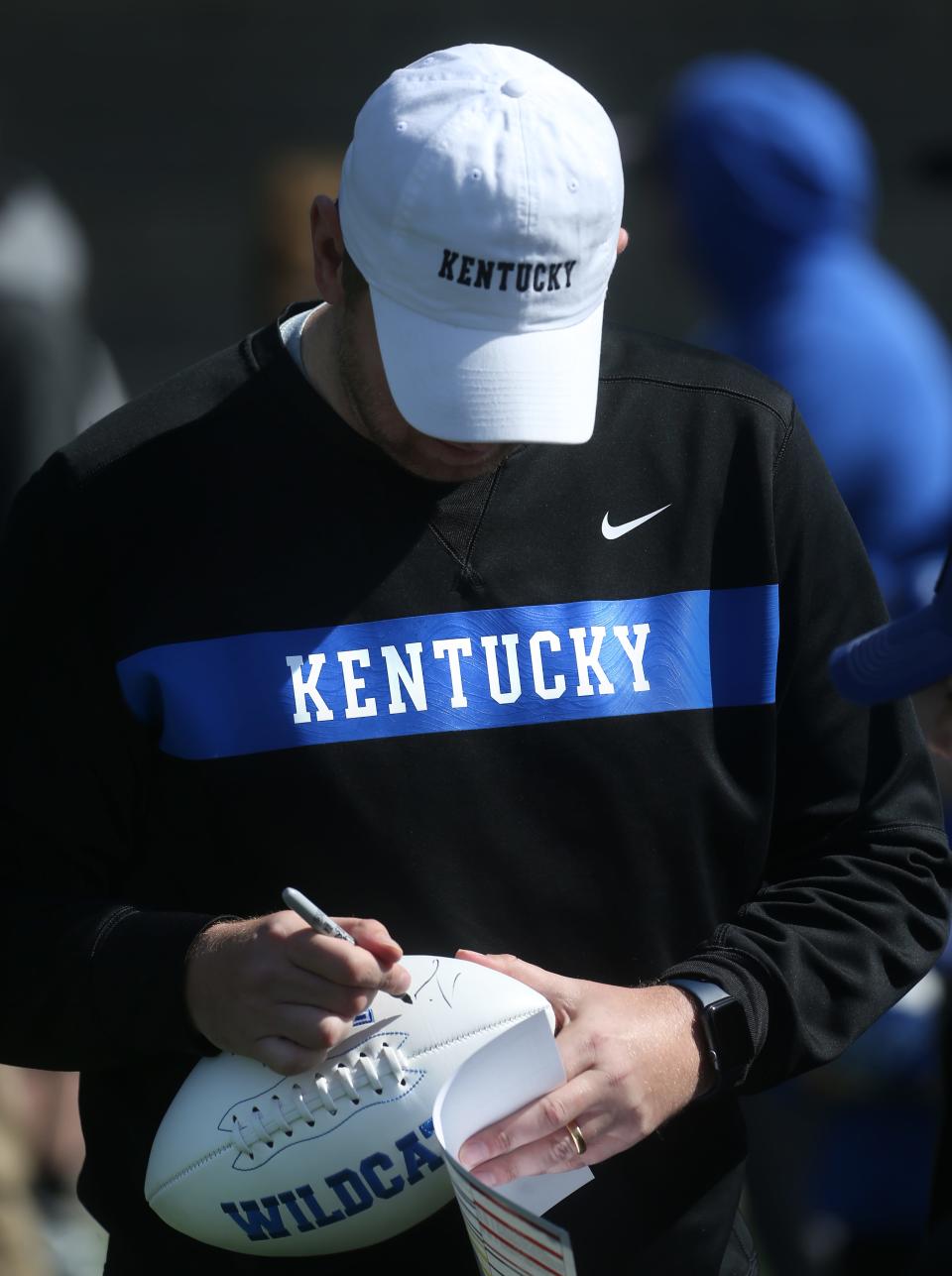 UK's Liam Coen signs a football during an open practice in April 2023.