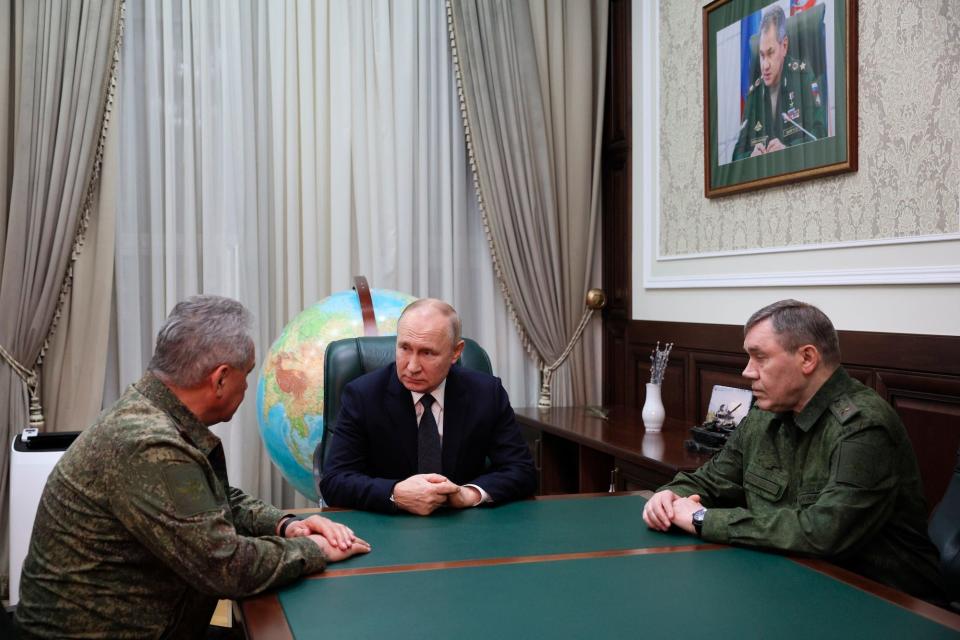 Russian President Vladimir Putin sits between Russian Defense Minister Sergei Shoigu, and Russian Chief of General Staff Gen. Valery Gerasimov at a green and wooden table