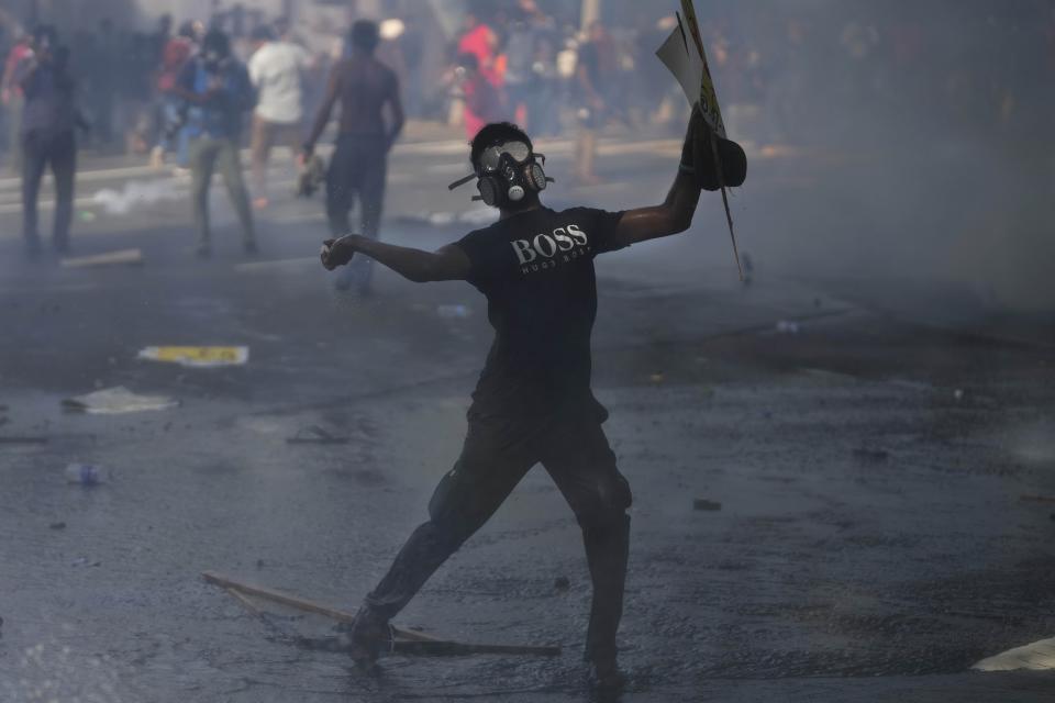 A member of the Inter University Students Federation throws fired tear gas canister back to police during an anti government protest in Colombo, Sri Lanka, Thursday, May 19, 2022. Sri Lankans have been protesting for more than a month demanding the resignation of President Gotabaya Rajapaksa, holding him responsible for the country's worst economic crisis in recent memory. (AP Photo/Eranga Jayawardena)