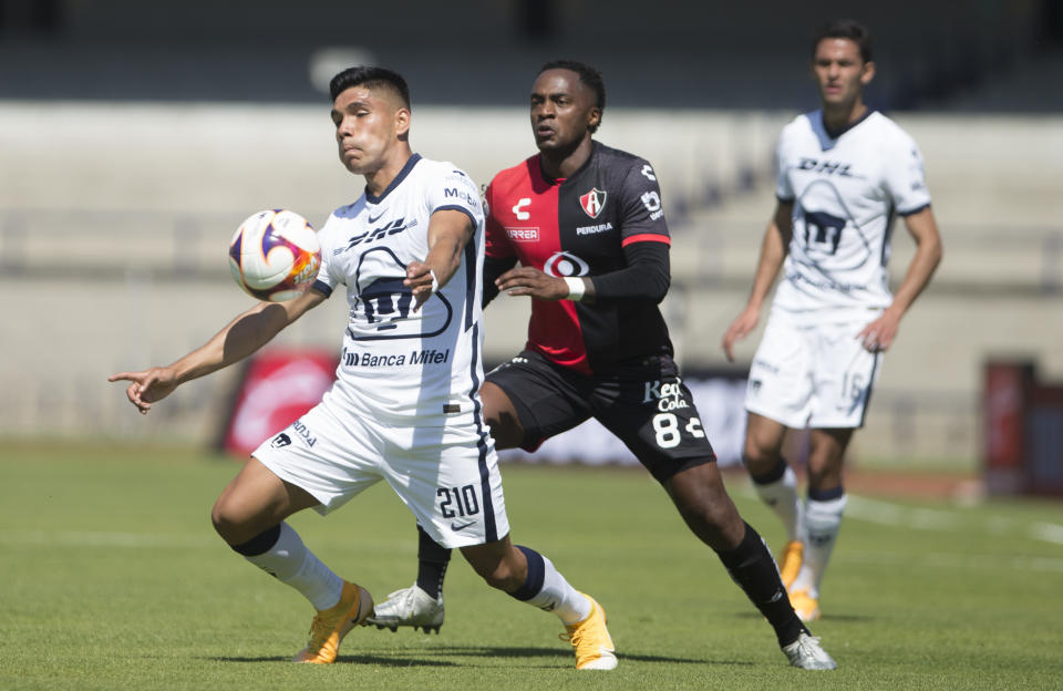 Emannuel Montejano (primer plano) de Pumas disputa un balón con Renato Ibarra de Atlas en el partido por el torneo Clausura de México, el domingo 31 de enero de 2021. (AP Foto/Christian Palma)