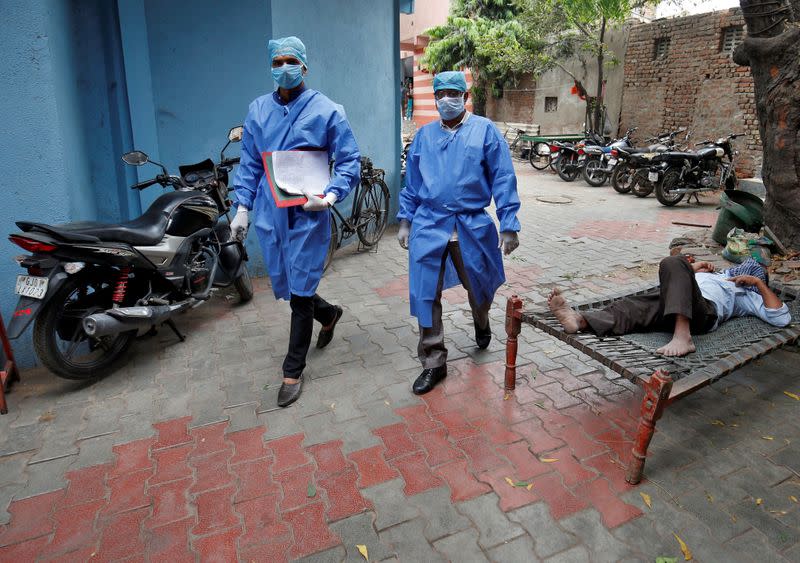 Police officers in protective suits arrive in a residential area to check on people under home quarantine in Ahmedabad