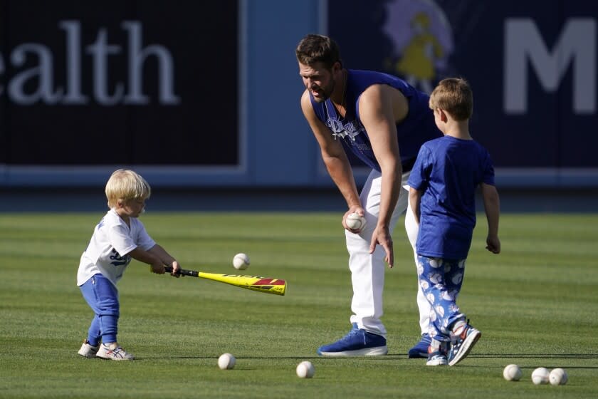 Los Angeles Dodgers pitcher Clayton Kershaw, center, pitches to his son Cooper, left, as his other son Charley watches prior to a baseball game between the Dodgers and the Arizona Diamondbacks Tuesday, May 17, 2022, in Los Angeles. (AP Photo/Mark J. Terrill)