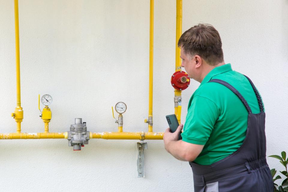 A worker in a green shirt installs gas lines.