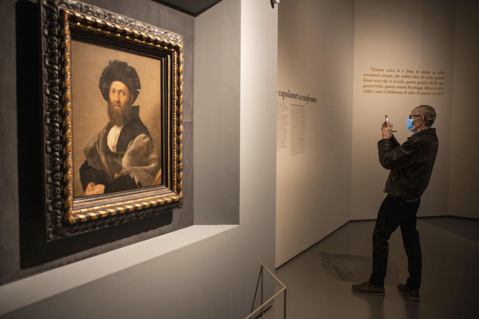 A man wearing a mask takes picture at a press preview of Raphael's exhibition in Rome, Wednesday, March 4, 2020. The paintings, drawings and sketches in the most ambitious assemblage ever of Raphael works in an exhibition, more than even the Renaissance superstar had in his workshop at one time, are collectively insured for 4 billion euros ($.4 billion), against the likes of theft or vandalism. But no money can guarantee that Italy’s outbreak of coronavirus, the largest in Europe, won’t play havoc with the three-month run in Rome of the art world’s eagerly-awaited blockbuster. (AP Photo/Domenico Stinellis)