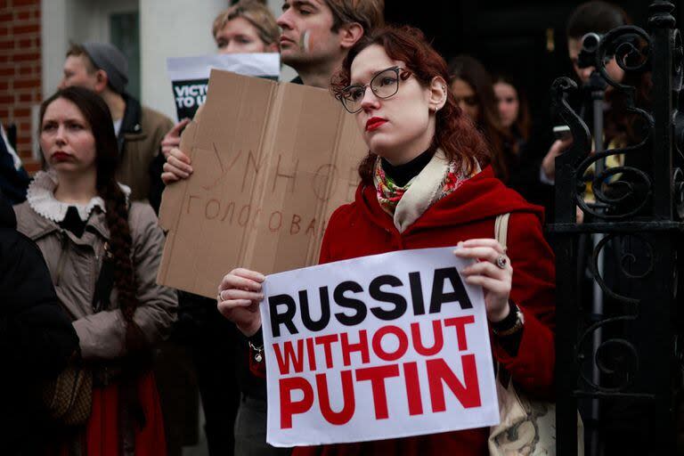 Los manifestantes sostienen pancartas mientras se reúnen frente a la embajada rusa, en Londres, el 17 de marzo de 2024 para protestar contra las elecciones presidenciales de Rusia.