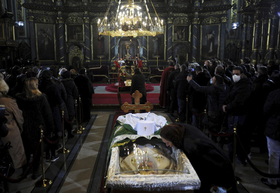 A woman kisses a protective screen over the coffin of Patriarch Irinej as he lies in repose at the Congregational church in Belgrade, Serbia, Saturday, Nov. 21, 2020. Mourners flocked to pay respects following the death of the Serbian Orthodox Church Patriarch Irinej, many ignoring preventive measures against the new coronavirus even though the head of the church died after contracting the virus himself. (AP Photo/Ana Paunkovic)
