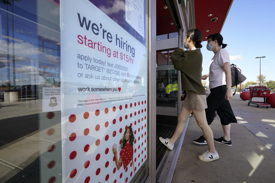 Passers-by walk past a hiring sign as they enter a Target retail store location, Wednesday, Sept. 30, 2020, in Westwood, Mass. The number of Americans seeking unemployment benefits declined last week to a still-high 837,000, evidence that the economy is struggling to sustain a tentative recovery that began this summer. (AP Photo/Steven Senne)