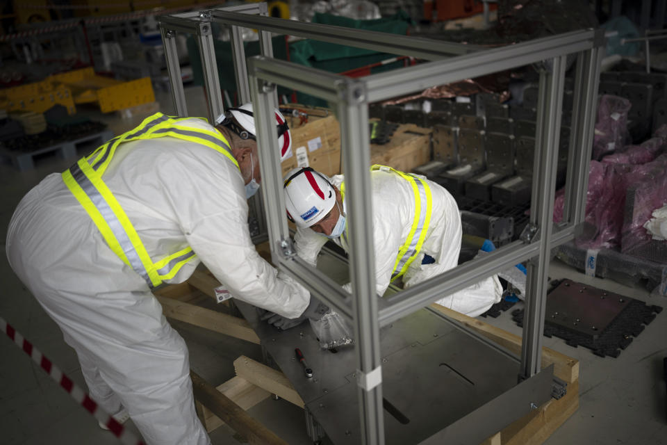 ITER project workers build components in Saint-Paul-Lez-Durance, France, Thursday, Sept. 9, 2021. Scientists at the International Thermonuclear Experimental Reactor in southern France took delivery of the first part of a massive magnet so strong its American manufacturer claims it can lift an aircraft carrier. (AP Photo/Daniel Cole)