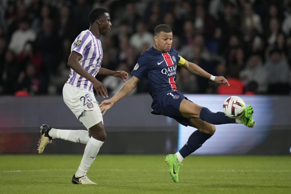 PSG's Kylian Mbappe, right, is challenged by Toulouse's Kevin Keben during the French League One soccer match between Paris Saint-Germain and Toulouse at the Parc des Princes stadium in Paris, Sunday, May 12, 2024. (AP Photo/Christophe Ena)