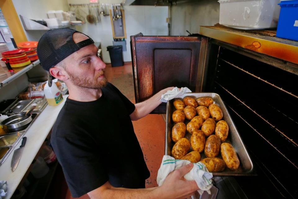 Eli Hardaker, cook, prepares baked potatoes at Mikey B's on Victoria Street of Acushnet Avenue in New Bedford.