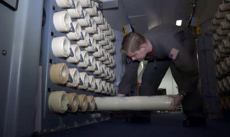 A member of the U.S. Navy, aboard the Boeing P-8A Poseidon plane, takes a sonobuoy to drop it at sea as they fly over the South Atlantic Ocean during the search for the ARA San Juan submarine missing at sea, Argentina November 22, 2017. A sonobuoy is an expendable sonar system that is ejected from aircraft or ships conducting anti-submarine warfare or underwater acoustic research. Picture taken November 22, 2017. REUTERS/Magali Cervantes