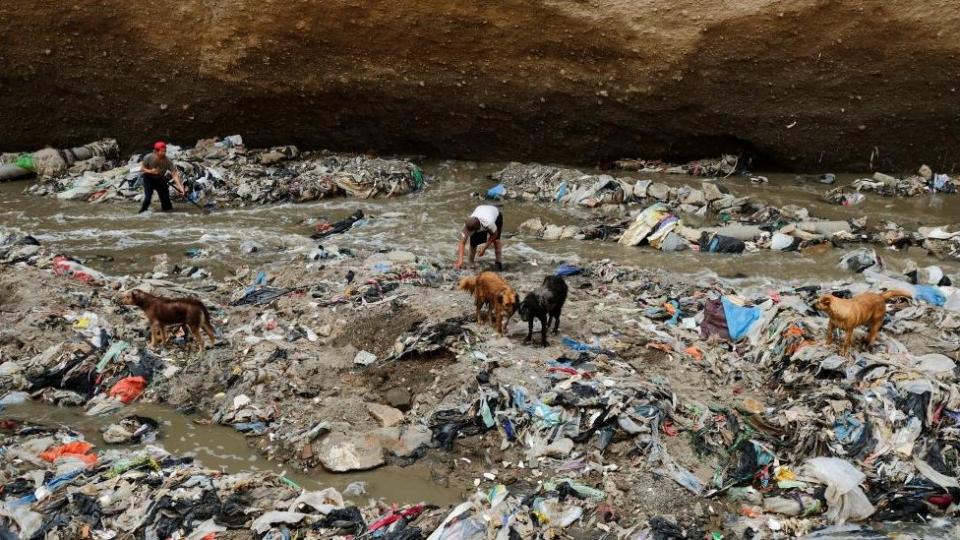 Un hombre busca chatarra en las aguas contaminadas del río Las Vacas