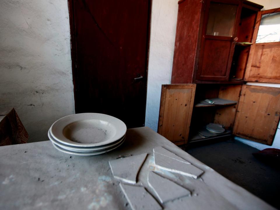 An abandoned house with plates on a table in Kleitos, Greece.