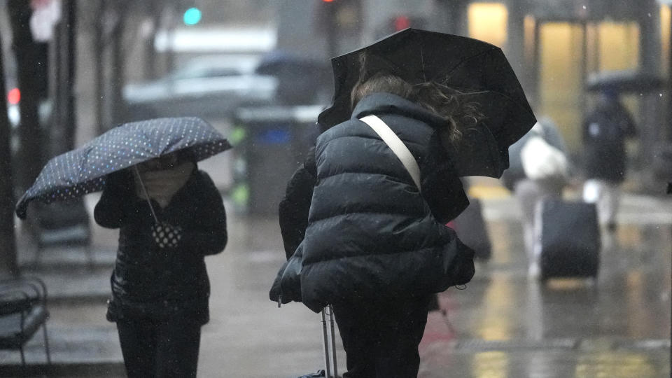 Commuters walk with umbrellas through wind-driven rain near South Station, Thursday, April 4, 2024, in Boston. (AP Photo/Charles Krupa)