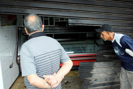 Men look at the damages in a butcher shop after it was looted in San Cristobal, Venezuela May 17, 2017. REUTERS/Carlos Eduardo Ramirez