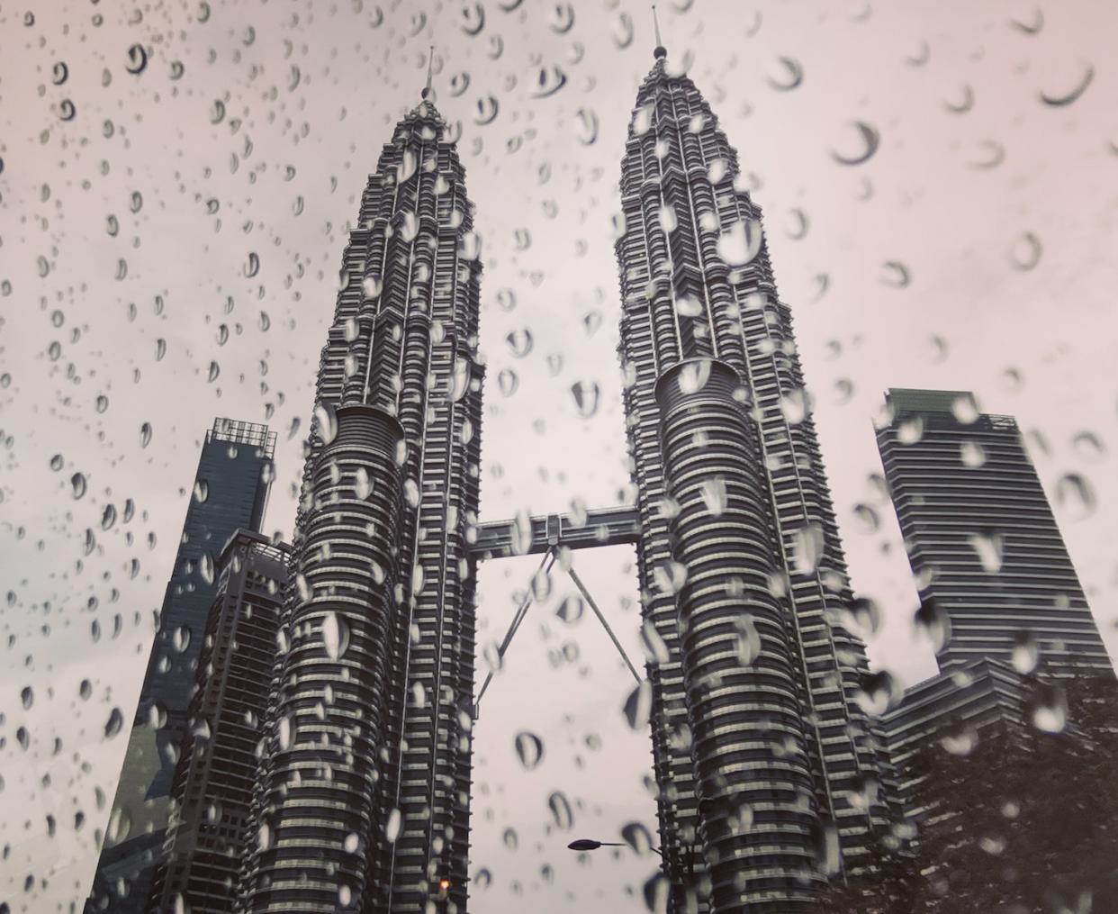 A picture of the Petronas Twin Towers in Kuala Lumpur, taken from behind a wet glass.