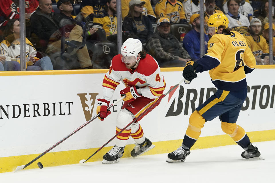 Calgary Flames' Rasmus Andersson (4) is defended by Nashville Predators' Cody Glass (8) in the second period of an NHL hockey game Tuesday, April 19, 2022, in Nashville, Tenn. (AP Photo/Mark Humphrey)